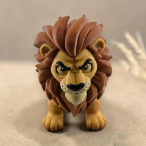 Lev – produktová fotografie s přírodním pozadím Pohyblivá 3D tištěná figurka lva se žlutým tělem a hnědou hřívou na pískovém podkladu.